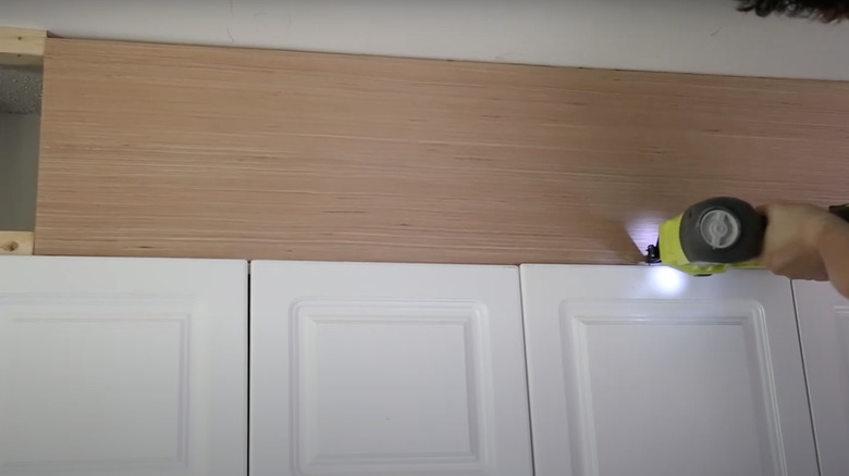 Installing wood panel above kitchen cabinets