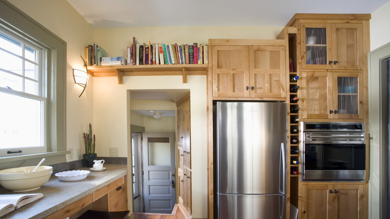 A row of cookbooks stored on a kitchen shelf