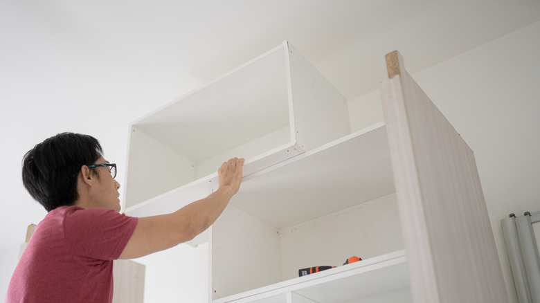 Person installing a box on top of cabinets