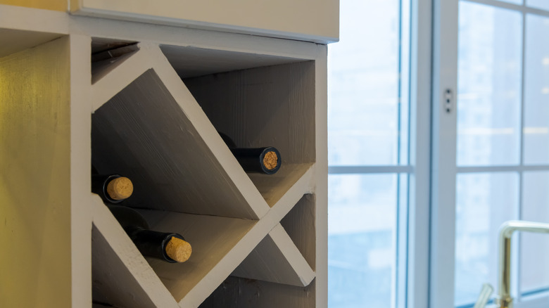 A close-up of a wine rack installed on top of kitchen cabinets