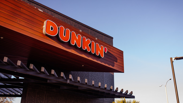 Closeup of logo sign of Dunkin' Donuts on the store facade with twilight sky in background
