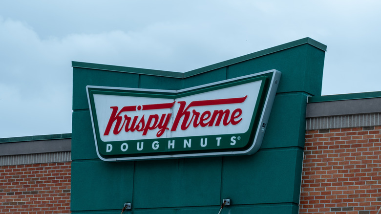 Closeup of Krispy Kreme restaurant sign against cloudy sky