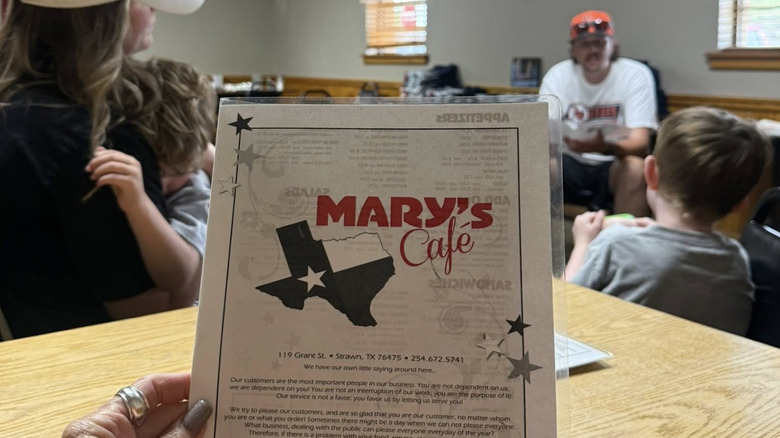 Woman holding a Mary's Cafe restaurant menu