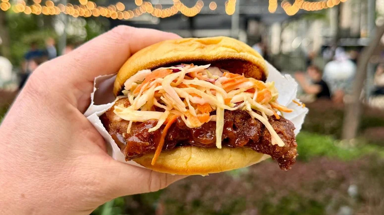 A person holding a Shake Shake BBQ rib sandwich
