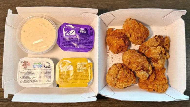 Taco Bell Diablo Dusted nuggets in a container next to four different dipping sauces