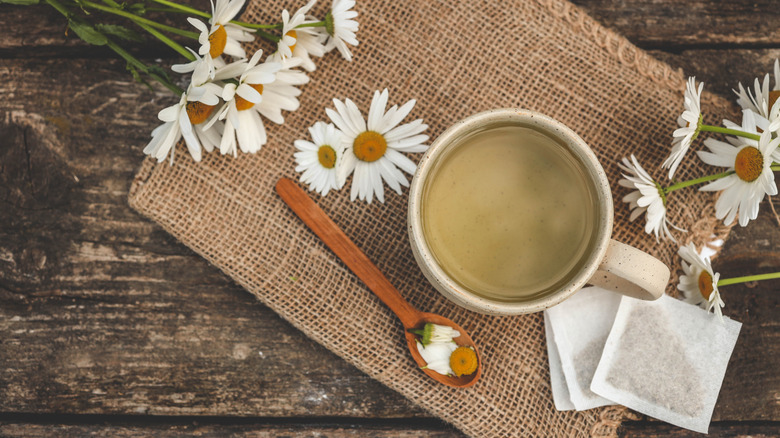 overhead view of cup with chamomile tea bag and flowers