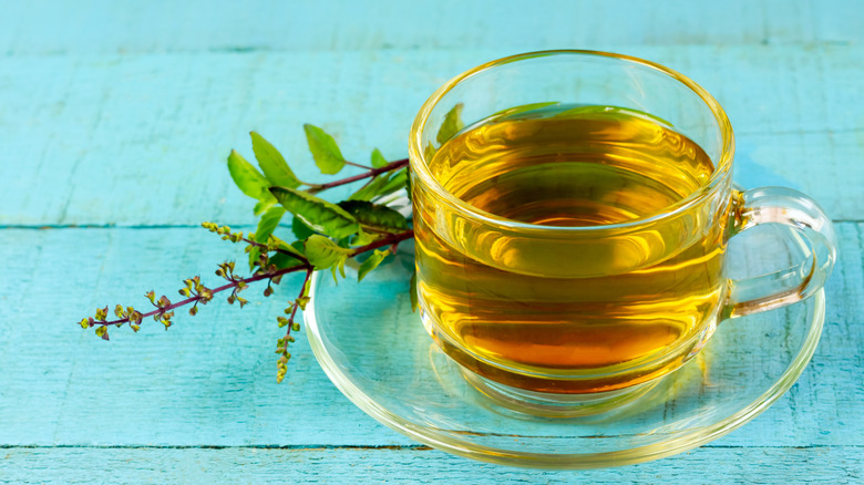 glass cup of holy basil tea on blue background