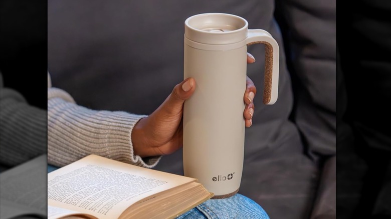 close up of a person holding a beige Ello Magnet 18oz Stainless Steel Travel Mug