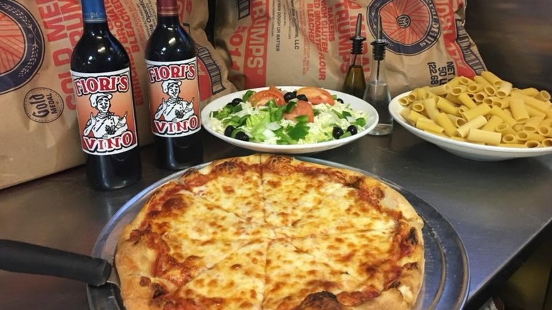 Pizza on counter with bottles of Fioro's wine, salad, and pasta