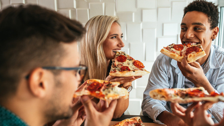 Group of happy friends eating pizza