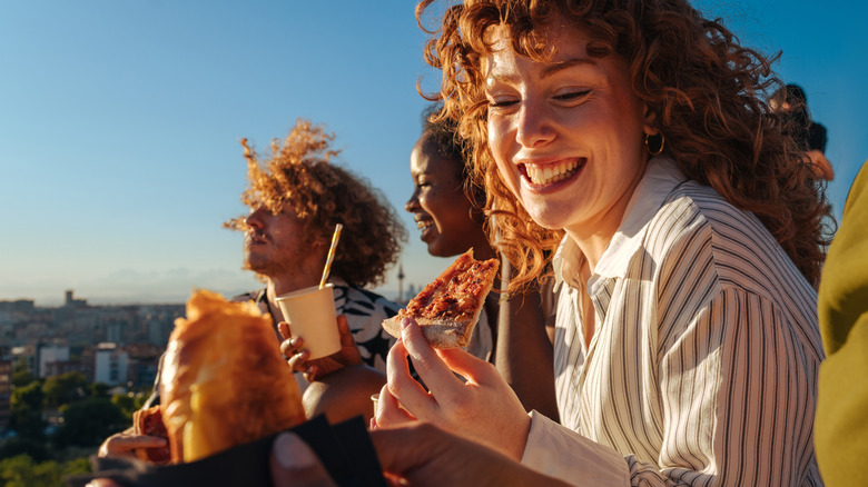 Friends sitting outside on a sunny day eating pizza