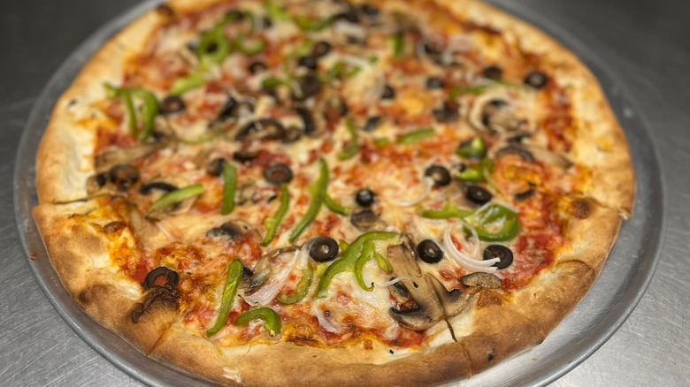 Pizza with peppers, olive, and mushrooms on silver tray