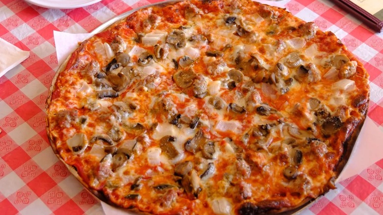 Thin crust pizza with mushrooms on red and white checked tablecloth