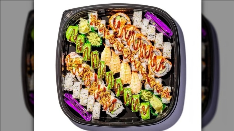 Member's Mark by FujiSan Big Maki Combo Platter with an assortment of sushi, soy sauce packets, wasabi, and pickled ginger on a white background