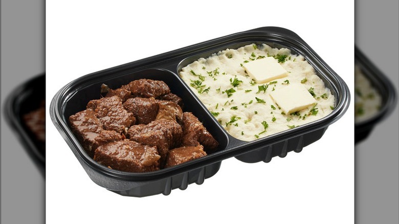 Kirkland Signature Braised Beef with Yukon Mashed Potatoes in a black deli container on a white background