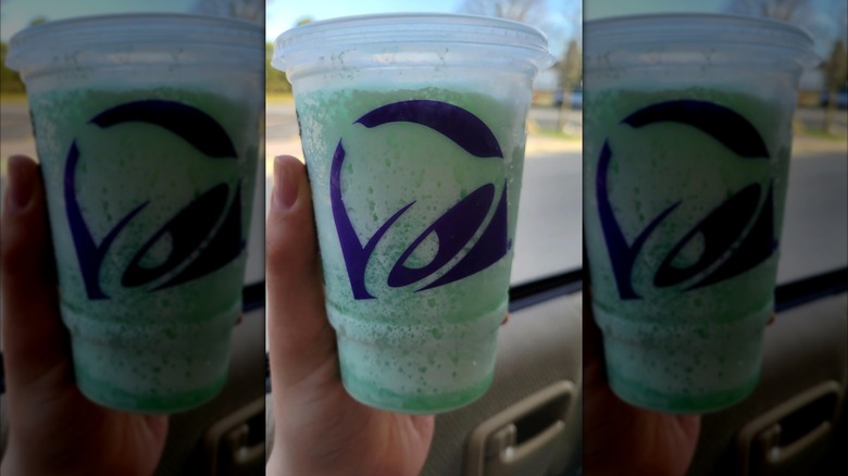 person holding Taco Bell Mountain Dew Baja Blast Dirty Soda Freeze in car