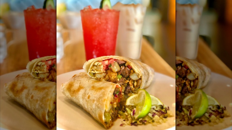 El Padre breakfast burrito sliced with lime and drinks in the background