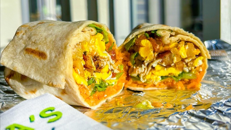 Two halves of breakfast burrito on foil