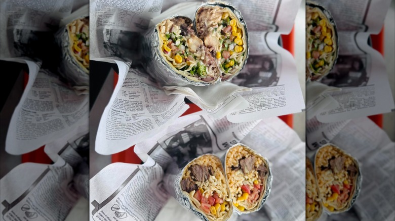 Two foil-wrapped burritos in trays with newspaper