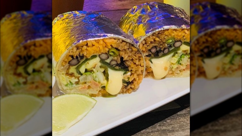 Burrito cut in half with rice, beans, and cheese-stuffed peppers