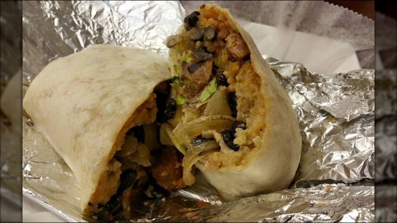 Two halves of a burrito on foil