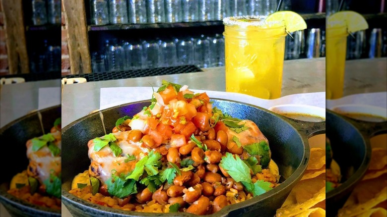 Burrito with beans in a cast iron skillet with cocktail