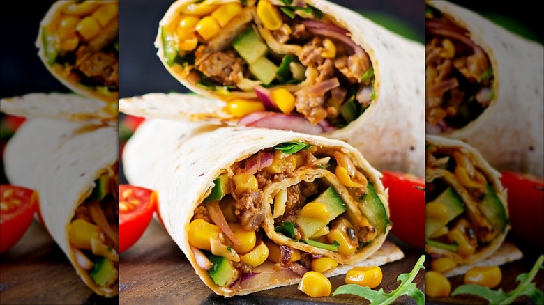 Two halves of a burrito with corn and veggies