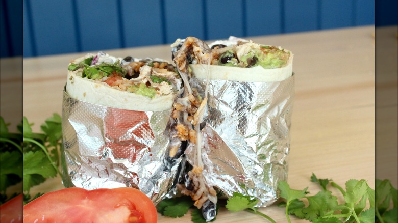Two halves of a burrito standing on end and wrapped in foil