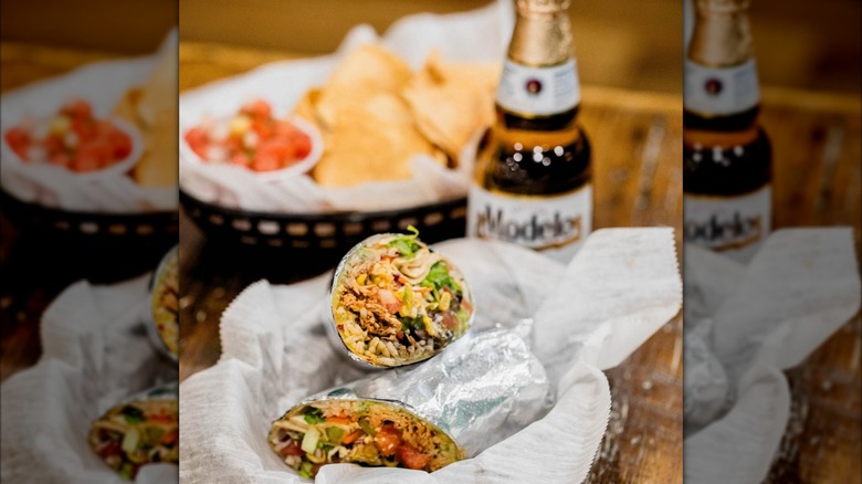 Burrito in basket with beer and side of chips and salsa