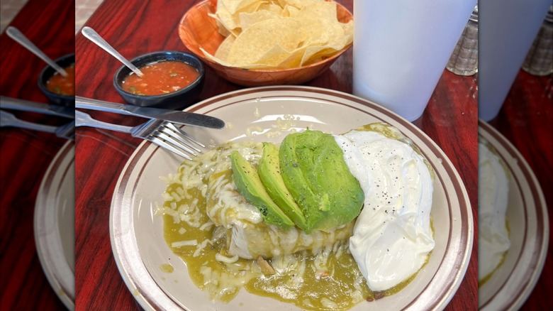 Plate with burrito, sliced avocado, and sour cream