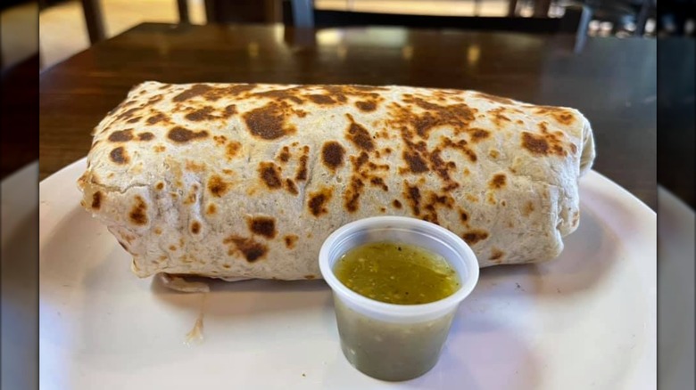 Massive burrito on a plate with green chile salsa