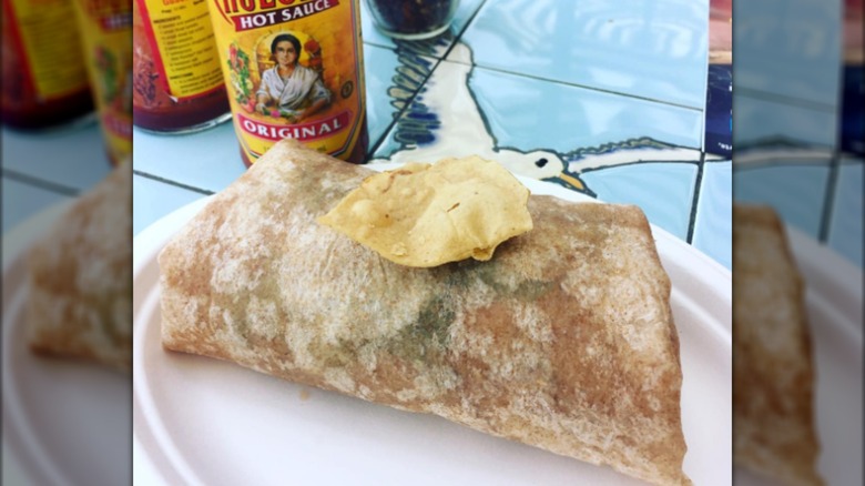 Burrito on a plate with hot sauce bottle