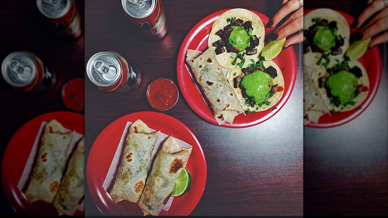 Two plates with baby burritos, tacos, and limes