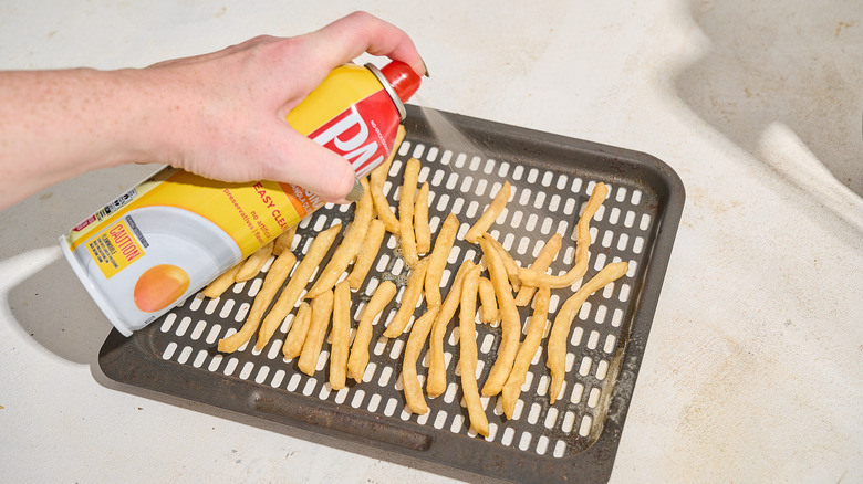 spraying french fries with oil