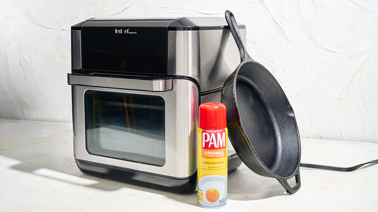 Air fryer, skillet, and cooking spray on a table