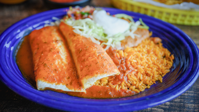Enchiladas on a blue plate with rice and beans