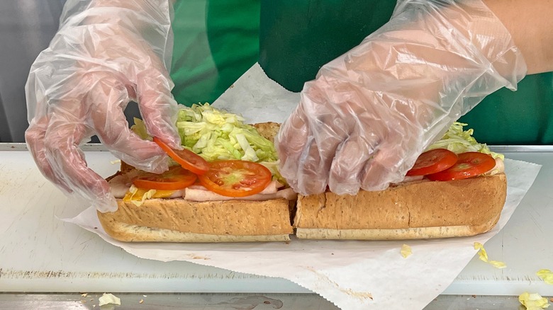 Worker preparing submarine sandwich