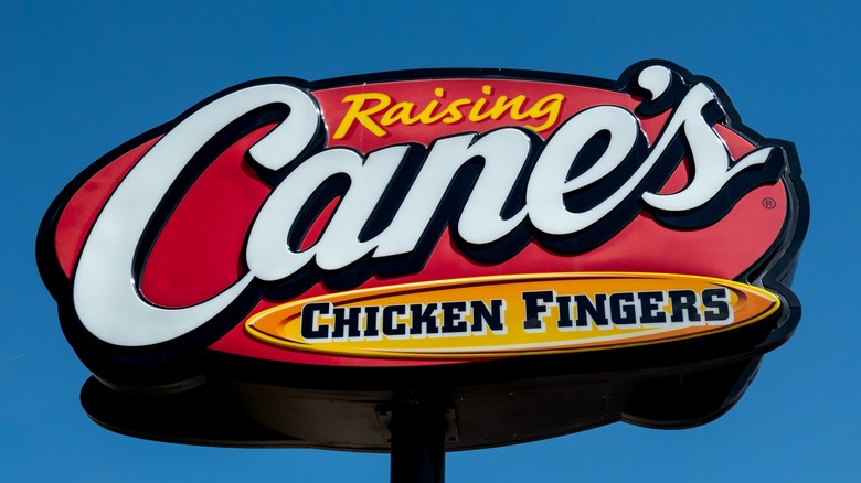 Raising Cane's Chicken Fingers sign against blue sky
