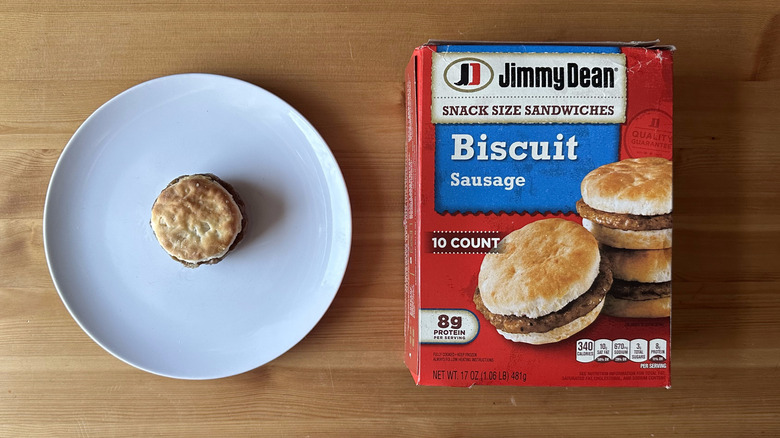 an overhead angle of a Jimmy Dean sausage biscuit on a plate beside the box that it came in