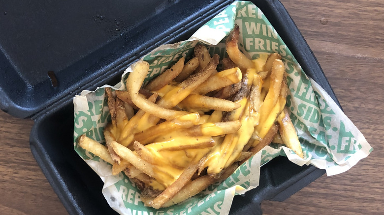 Cheese fries from Wingstop inside black styrofoam takeout container