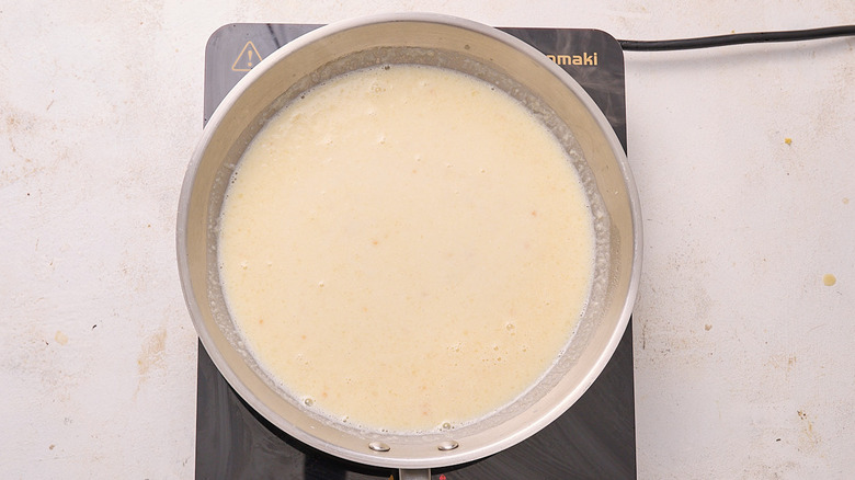 cooking broth and milk in skillet
