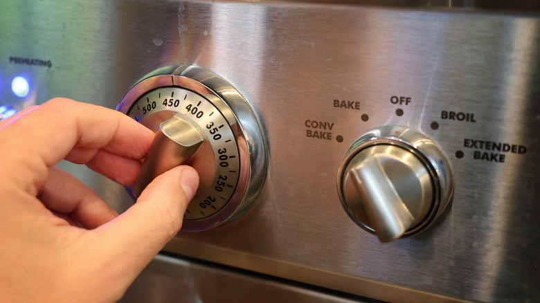 hand turning stainless steel oven dial to 450 F