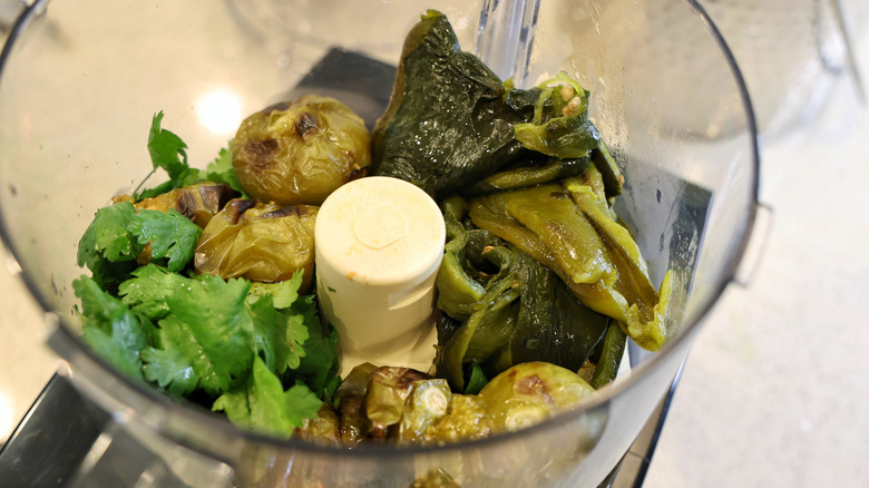 roasted tomatillos and peppers in a food processor with cilantro