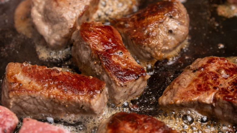 searing steak cubes in pan