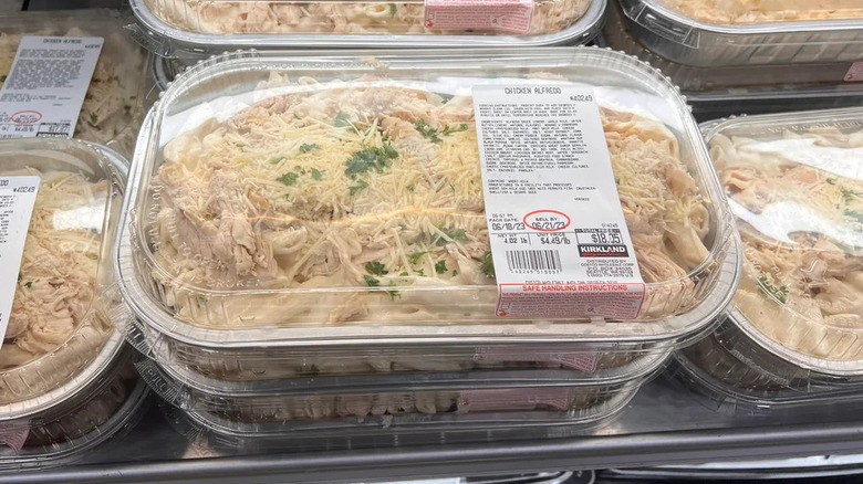 Stack of Costco chicken Alfredo containers in the store's refrigerator