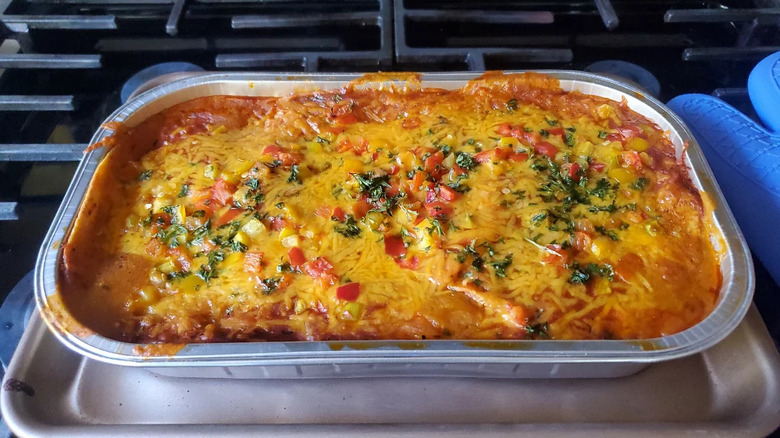 Prepared Costco chicken enchilada bake sitting on a sheet pan atop a stove