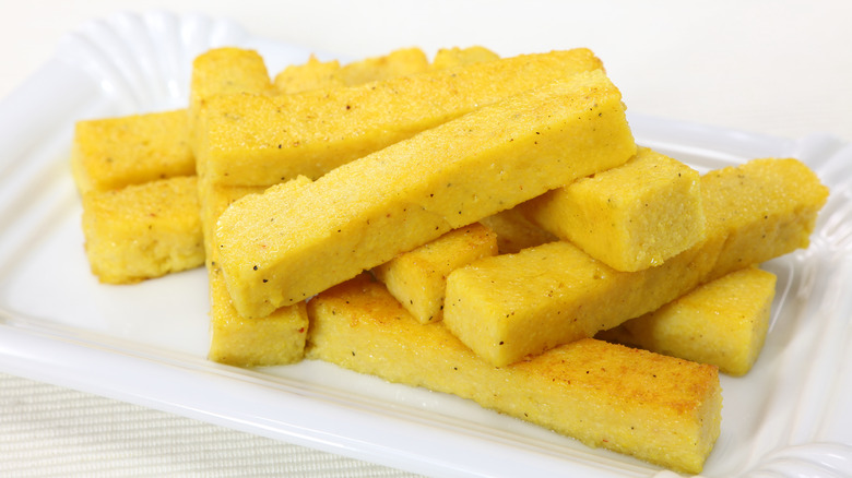 Golden strips of fried cornmeal mush, shown on a small, decorative, rectangular white platter