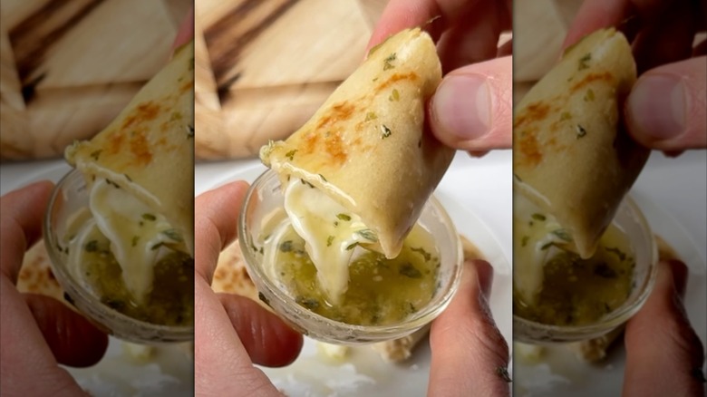 Hand dipping tortilla mozzarella stick into dip