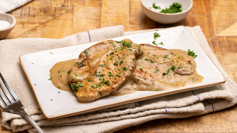 A plate of pork chops covered in mushroom sauce