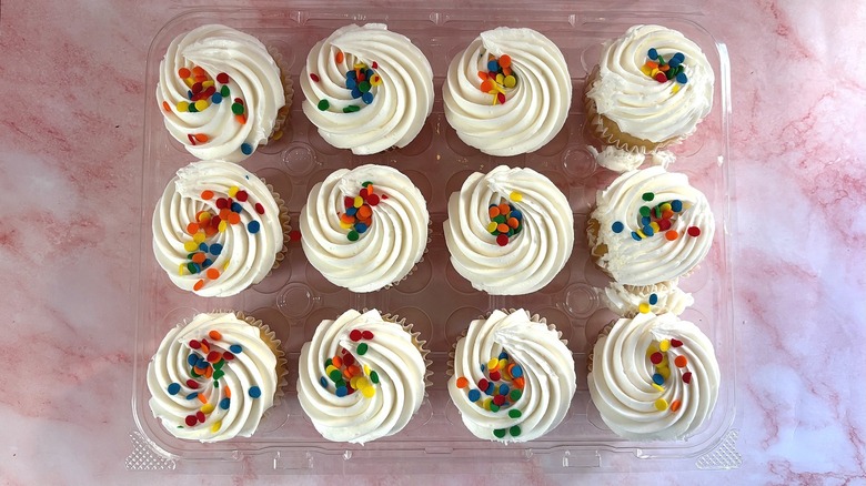 tray of decorated white cupcakes